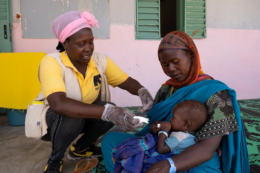 A health worker treats a nine-month-old Sudanese refugee girl held by her mother at a camp in Chad